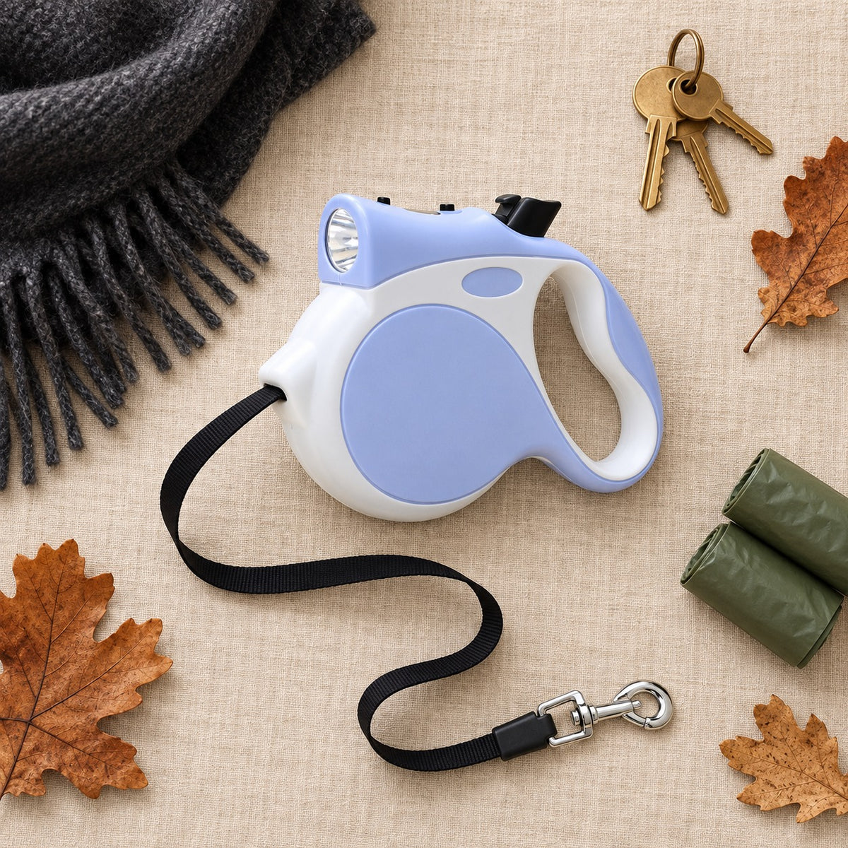Flat lay of the PETHART retractable dog leash with LED light alongside a scarf, keys and waste bags